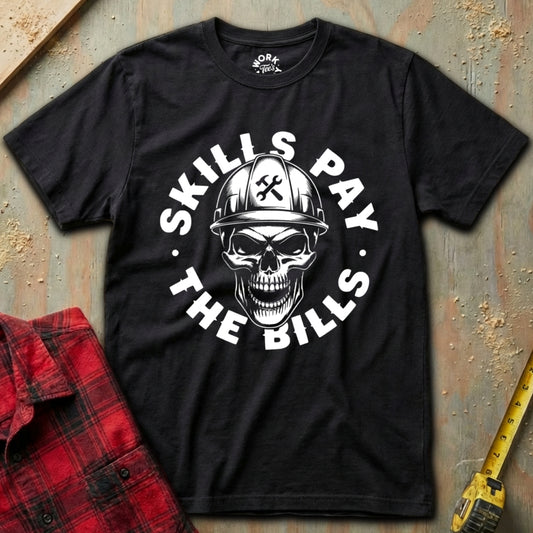 Black t-shirt with skull and hard hat graphic and 'Skills Pay the Bills' text on a textured surface.