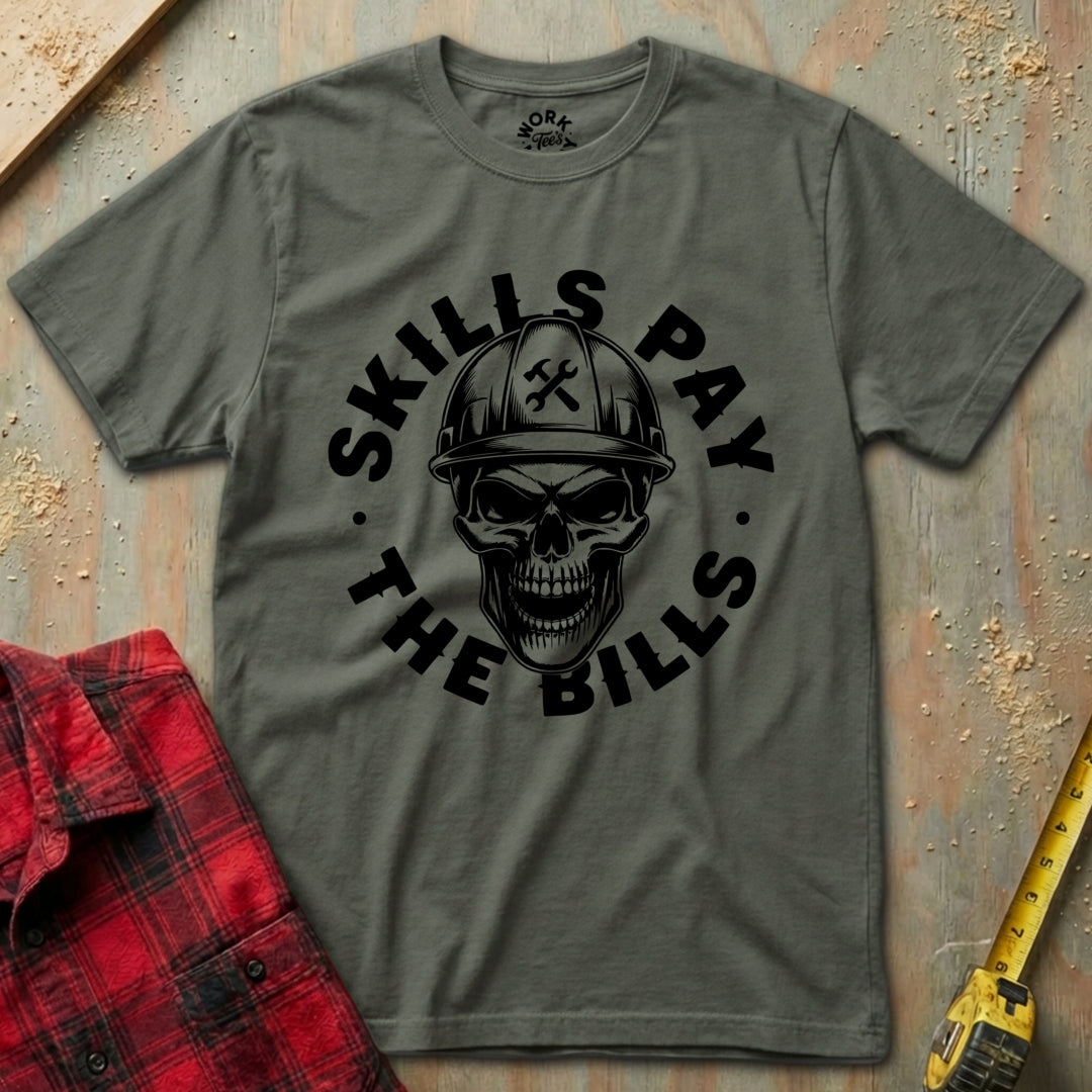 Gray t-shirt with skull graphic and 'Skills Pay the Bills' text on a textured surface.