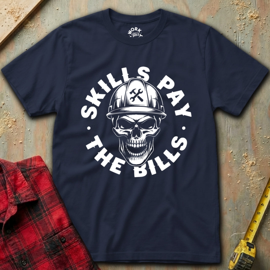 Navy blue t-shirt with skull and hard hat graphic and 'Skills Pay the Bills' text on a textured surface.