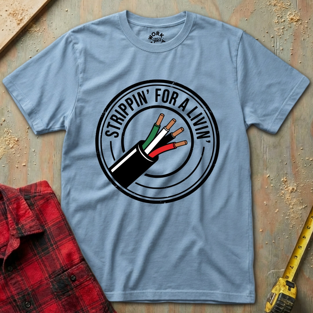 Light blue t-shirt with a graphic design and text on a wooden surface with a red shirt and tape measure.
