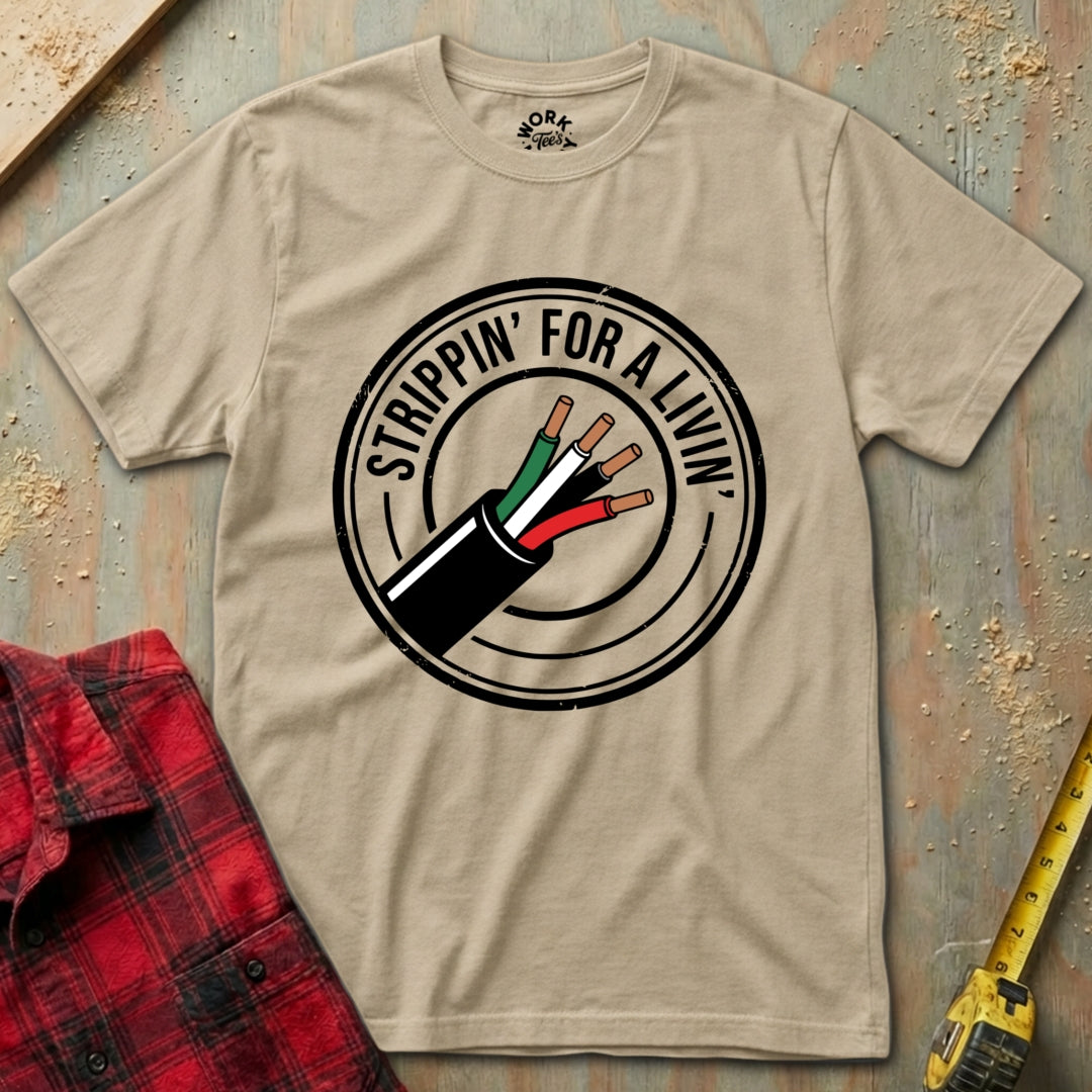 Beige t-shirt with a graphic design of electrical wiring and text 'Strippin' for a Livin', placed on a wooden surface with tools.
