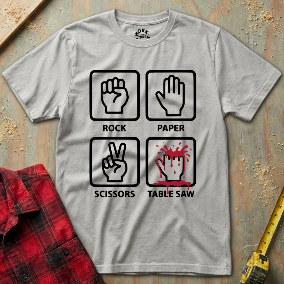 Gray t-shirt with graphic design of rock, paper, scissors, and table saw on a wooden surface.
