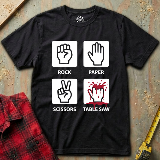 Black t-shirt with hand gestures and text on a textured surface with a red plaid shirt and yellow tool in the background.