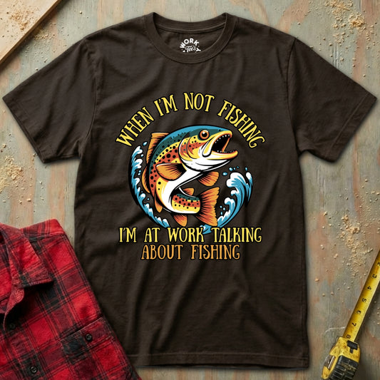Brown t-shirt with fishing graphic and text on a textured surface