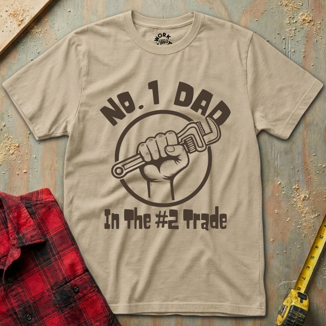 Beige t-shirt with 'No. 1 Dad in the #2 Trade' graphic on a rustic wooden background.